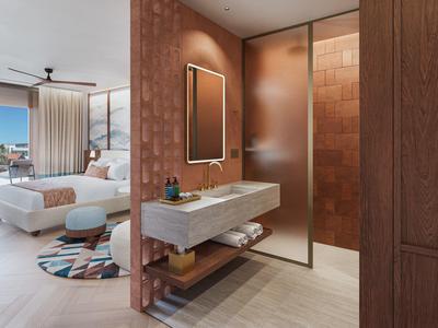 Moderní hotelový pokoj s bílou postelí, umyvadlem a kulatým kobercem v teplých tónech.