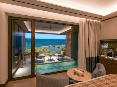 Výhled z pokoj hotelu na terasu s bazénem, mořem a krajinou v pozadí.