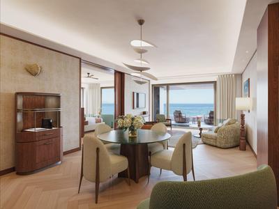 Světý obývací pokoj s jídelním koutem, výhledem na moře a moderním zařízením v světlém dřevě a krémových tónech.