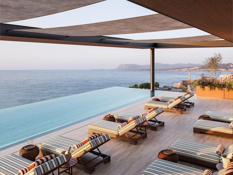 Infinity bazén s lehátky a výhledem na moře na terase při západu slunce.