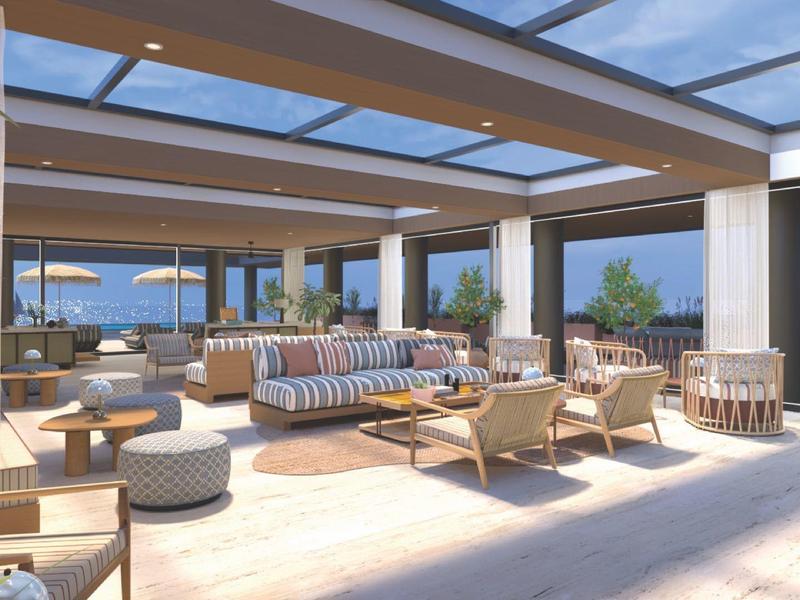 Světlá, moderní hala s posezením a velkými okny s výhledem na moře.