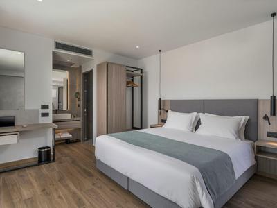 Camera d'hotel moderna con letto matrimoniale, testiera grigia e pavimento in legno.