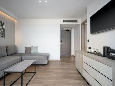 Nowoczesny pokój hotelowy z sofą, stolikiem kawowym i telewizorem na ścianie.