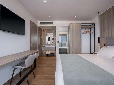 Camera d'hotel moderna con letto matrimoniale, TV e armadio aperto.