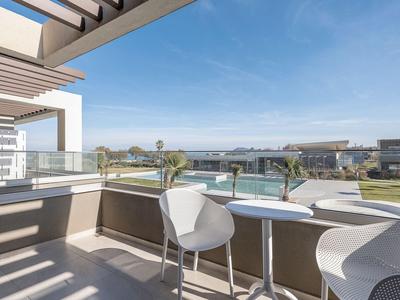 Balcone con tavolo e sedie moderne, vista sulla piscina e sulla città sullo sfondo.