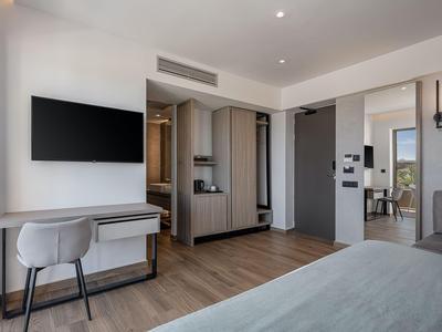 Nowoczesny pokój hotelowy z telewizorem na ścianie, biurkiem, krzesłem i widokiem na łazienkę.