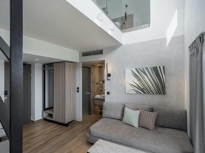 Chambre d'hôtel moderne avec canapé, sol en bois et salle de bain ouverte.