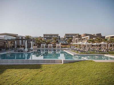 Grande piscina all'aperto con ombrelloni e sdraio in un resort alberghiero sotto un cielo limpido.