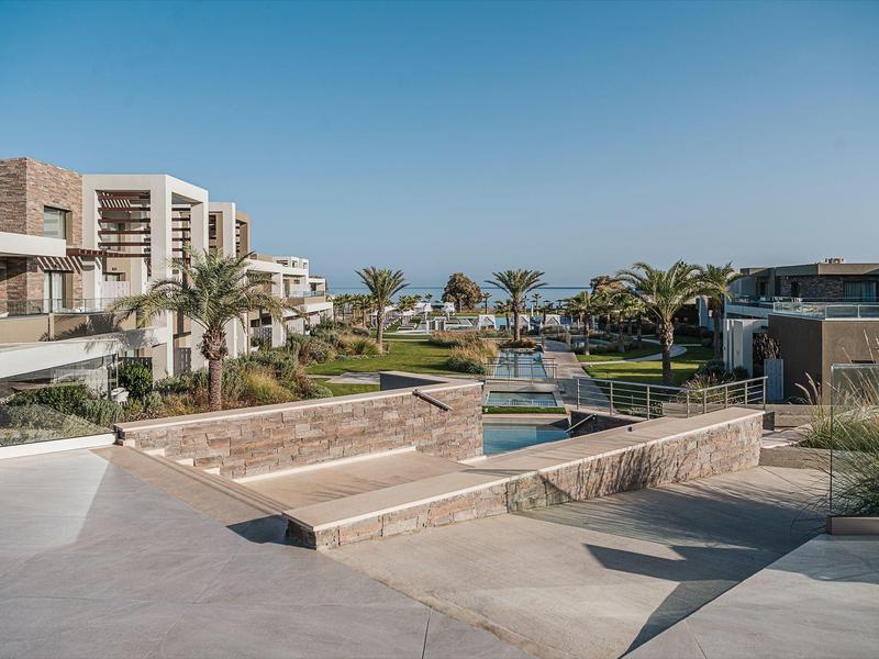 Complexe hôtelier moderne avec piscine et palmiers sous un ciel clair