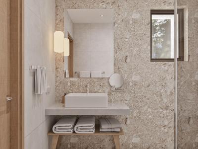 Baño moderno de hotel con paredes de mármol, espejo rectangular y lavabo con toallas.