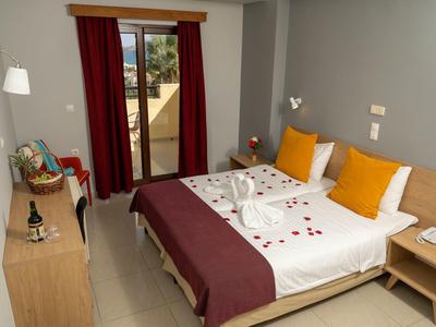 Modern hotel room with double bed, gray walls, and balcony overlooking outside.