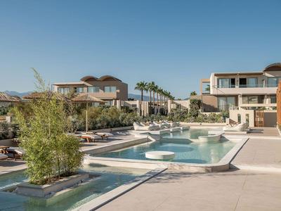 Moderner Poolbereich mit Liegen und Grünpflanzen in einem sonnigen Hotelresort