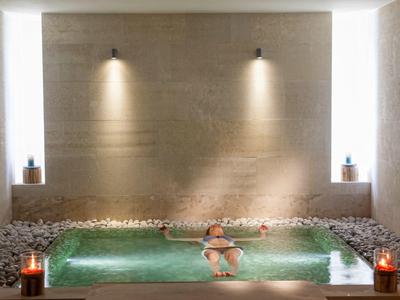Mujer relajándose en un jacuzzi iluminado en una habitación de diseño minimalista.