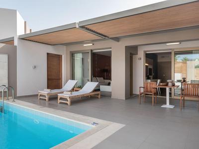 Área exterior moderna con piscina, tumbonas y acceso al interior de un hotel o casa de vacaciones.