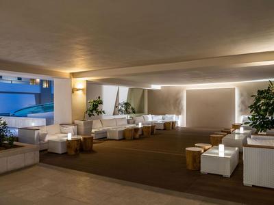 Modernes Lounge-Bereich mit weißen Sofas, Tischen und indirekter Beleuchtung in einem Hotel.