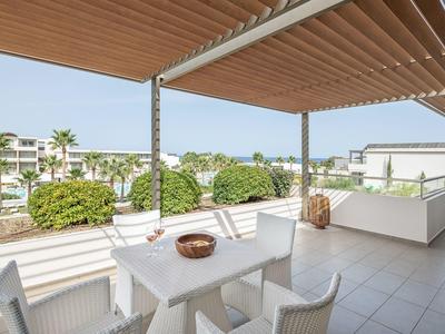 Terraza moderna con muebles blancos y vista a áreas verdes y edificios.