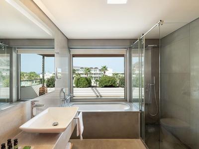 Baño luminoso con ducha de vidrio, lavabo y ventana con vista al área verde.