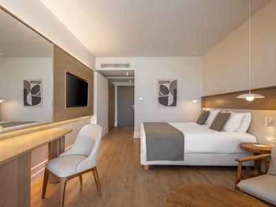 Habitación de hotel moderna con cama doble, escritorio, silla y suelo de madera.