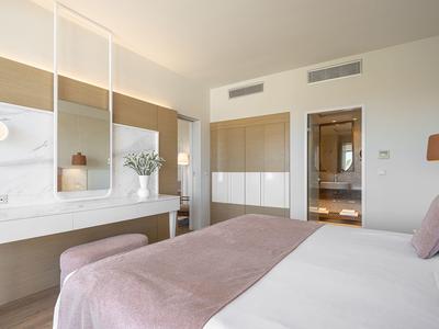 Habitación de hotel moderna con cama grande, espejos y vista al baño.