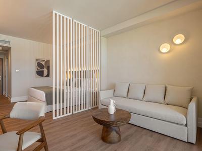 Habitación de hotel moderna con sofá, sillones y elegante separador de ambiente.