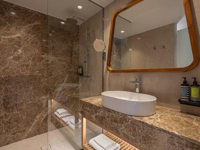 Baño moderno con encimera de mármol, lavabo ovalado y espejo rectangular con marco de madera.