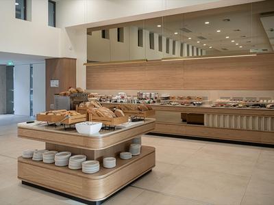 Modernes Hotelbuffet mit einer Vielzahl von Broten und Geschirr auf hellem Holz.