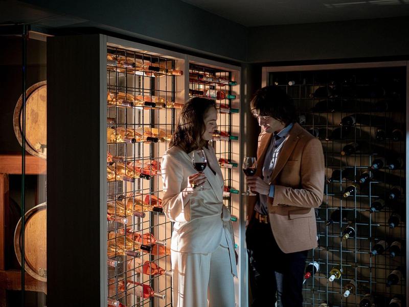 Pareja en ropa elegante junto a una bodega iluminada en un hotel de lujo.