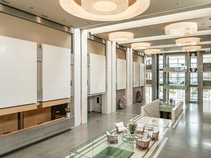 Área luminosa y moderna del vestíbulo del hotel con ventanas de vidrio y grupos de asientos minimalistas.