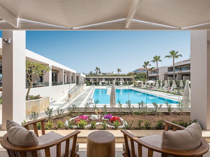 Moderna piscina de hotel con tumbonas y palmeras bajo cielo despejado.