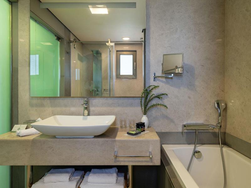 Baño moderno con lavabo, espejo, bañera y pared de acento verde.
