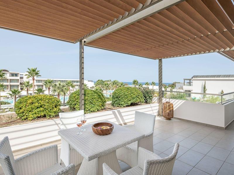 Terraza moderna con muebles blancos y vista a áreas verdes y edificios.