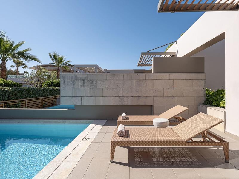 Área moderna de piscina al aire libre con dos tumbonas y toallas enrolladas en un día soleado