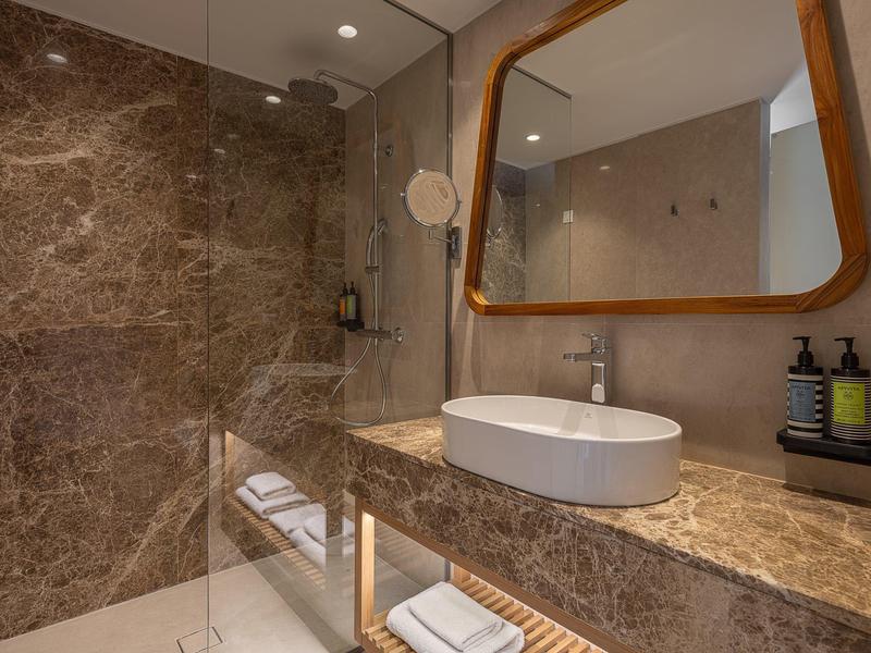 Baño moderno con encimera de mármol, lavabo ovalado y espejo rectangular con marco de madera.