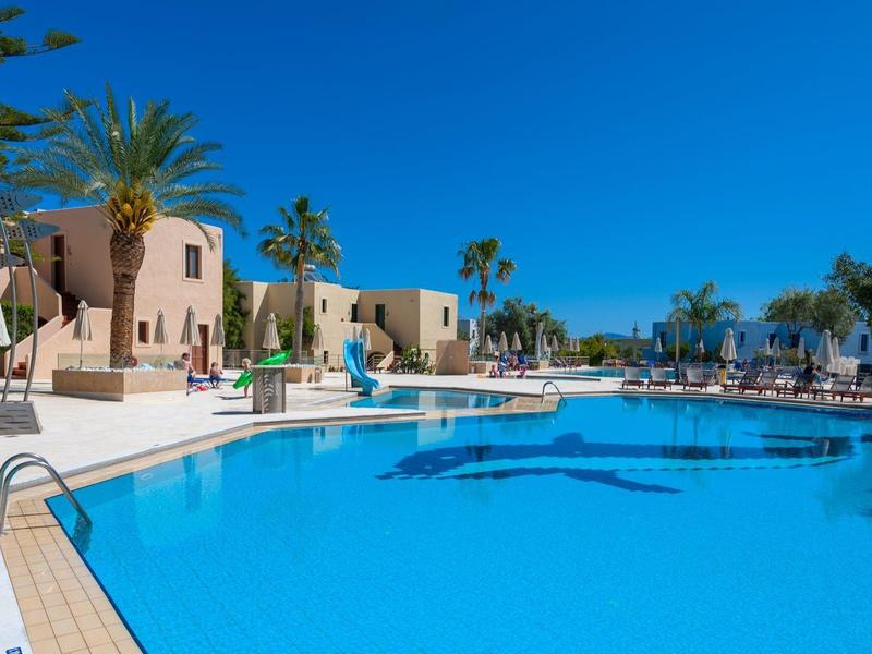 Gran piscina de hotel con superficie de agua azul y palmeras bajo cielo despejado.