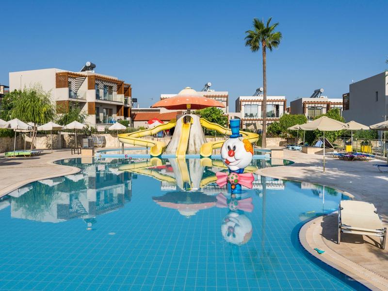 Gran piscina con toboganes de agua y tumbonas en un complejo hotelero bajo cielo azul.