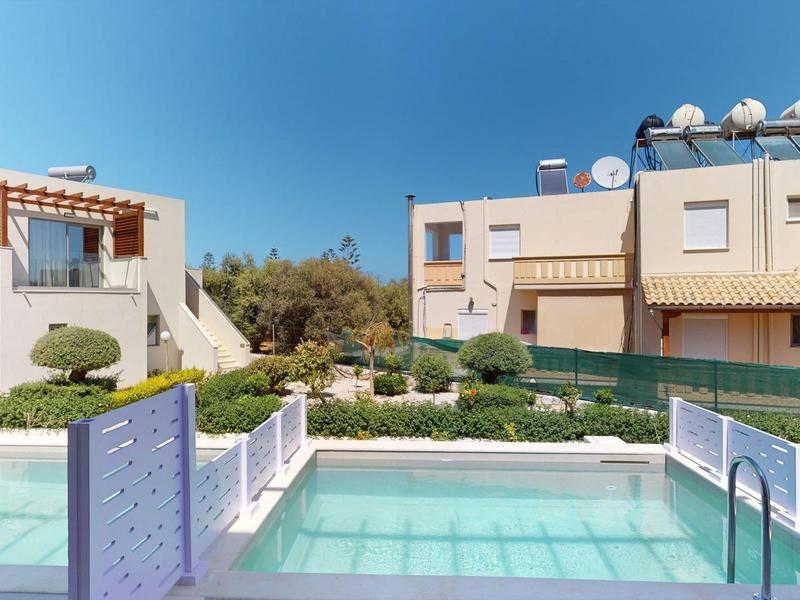 Zona de jardín con piscina y casas de vacaciones modernas bajo un cielo despejado