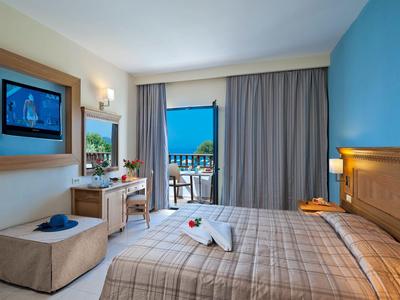 Chambre d'hôtel moderne avec lit double, bureau et balcon avec vue sur la mer.