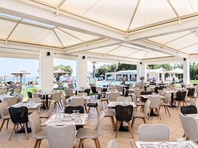 Restaurant d'hôtel ouvert avec tables dressées et vue sur une terrasse en plein jour.