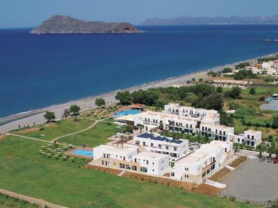 Hotel nad morzem z plażą, wyspami w tle i zielonymi polami.