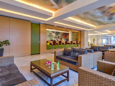 Eleganckie lobby hotelowe z miejscami do siedzenia, roślinami i dekoracyjnym oświetleniem sufitowym.