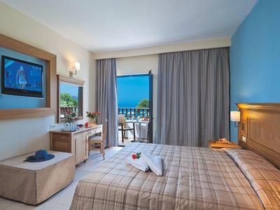 Nowoczesny pokój hotelowy z łóżkiem podwójnym, biurkiem, balkonem i widokiem na morze.