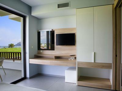 Nowoczesny pokój hotelowy z drewnianymi meblami i balkonem z widokiem na zielony krajobraz.