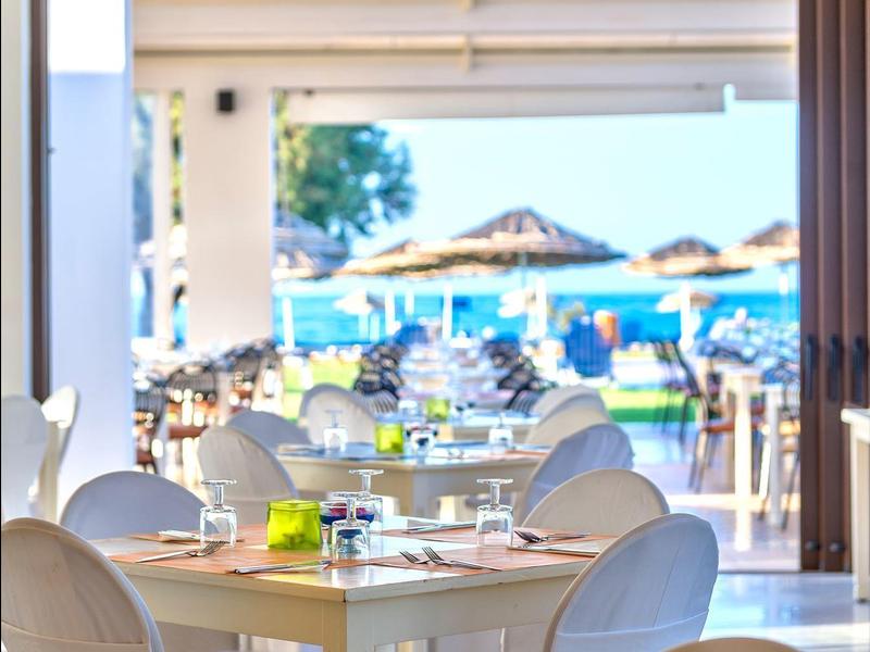 Jasna przestrzeń restauracyjna na zewnątrz z widokiem na plażę i morze.