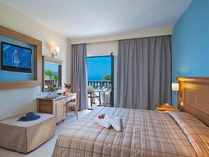 Nowoczesny pokój hotelowy z łóżkiem podwójnym, biurkiem, balkonem i widokiem na morze.