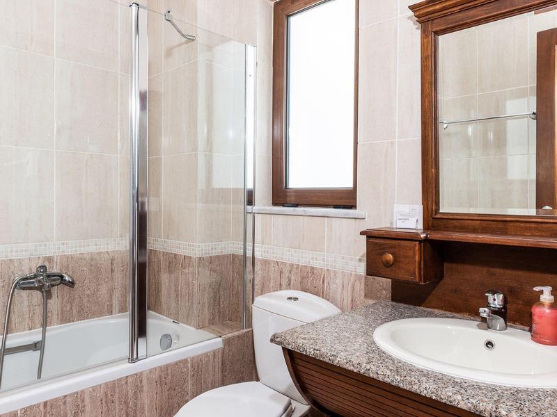 Jasna łazienka z wanną, toaletą i umywalką z dużym lustrem.