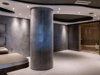 Espace bien-être moderne avec sauna, pilier en béton et éclairage tamisé.