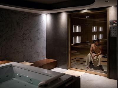 Un homme détendu est assis dans un sauna bien éclairé à côté d'un jacuzzi.