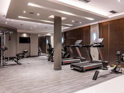 Salle de sport moderne avec tapis de course, rameur et équipements de musculation dans un hôtel.