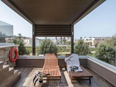 Balcon moderne avec transats en bois donnant sur des jardins soignés dans une résidence.