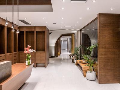 Couloir d'hôtel moderne avec sols clairs, boiseries et plantes décoratives le long du couloir.